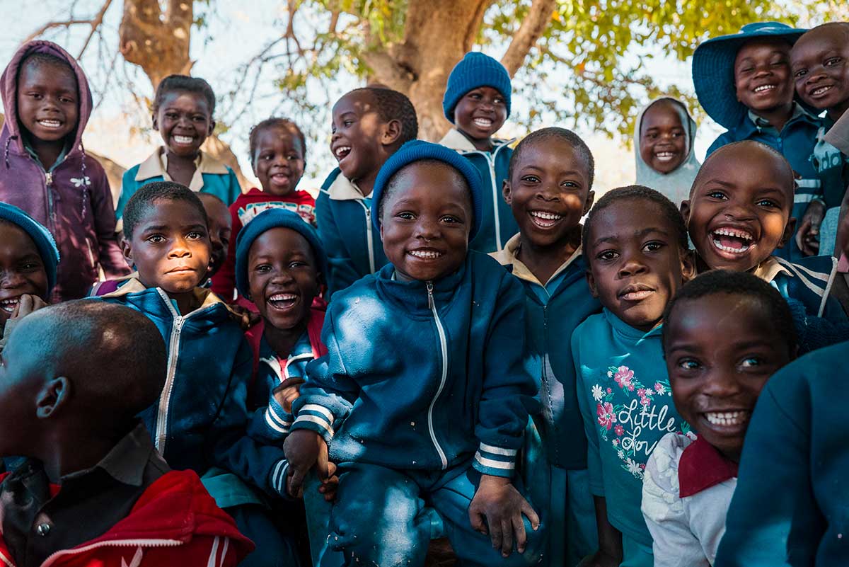 Gruppo di bambini sorridenti con la divisa scolastica che guardano la fotocamera