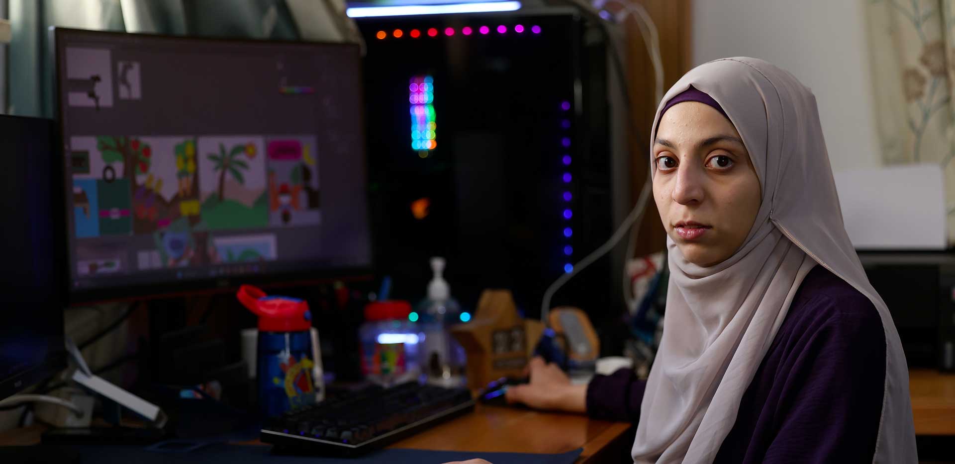 Hanin guarda verso l'obiettivo mentre è seduta alla scrivania dove elabora i disegni dei giocattoli.