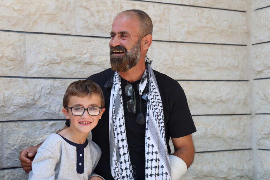 Mamohud sorridente insieme a suo nipote. Ha un braccio fasciato legato al collo.