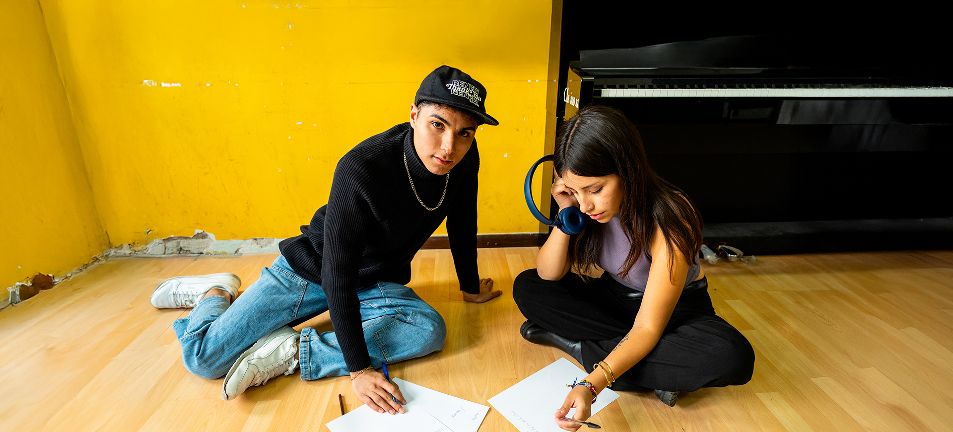 Matteo e Denise seduti per terra intenti a scrivere e ascoltare musica
