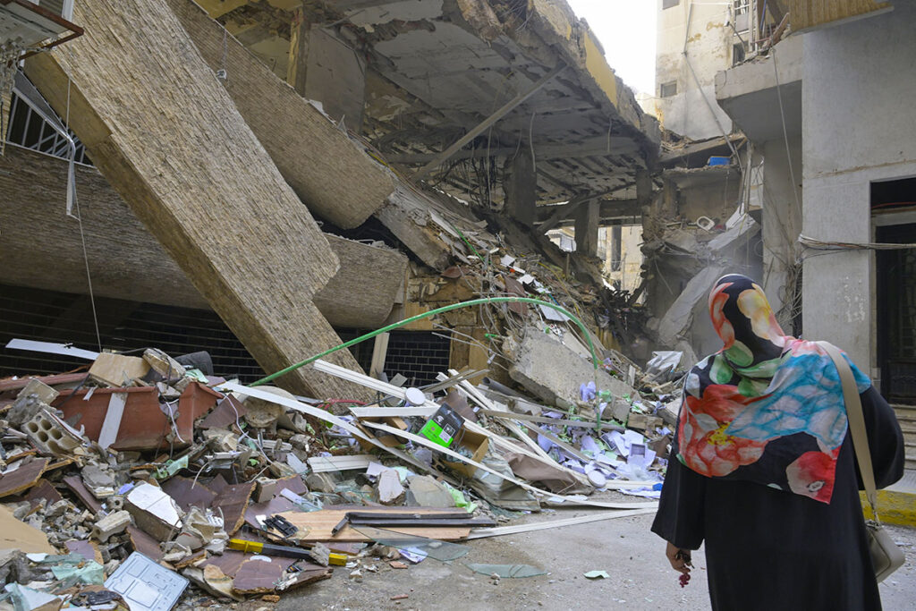 Una donna vista di spalle guarda sconsolata le macerie della sua casa dopo l'ultima attacco di Israele in Libano.