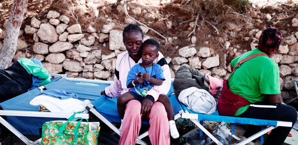 Una mamma, seduta su una brandina di emergenza, tiene in braccio il suo bambino.