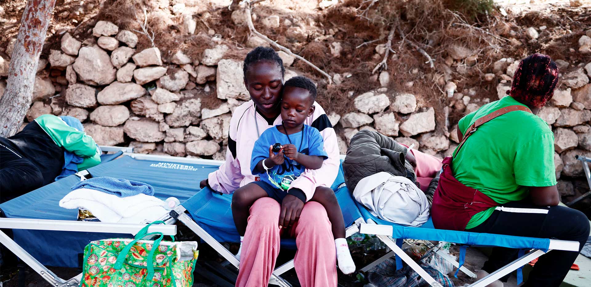 Una mamma, seduta su una brandina di emergenza, tiene in braccio il suo bambino.