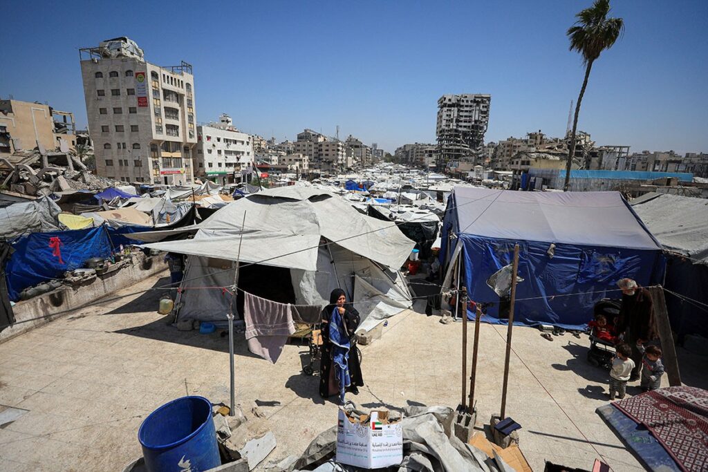 Una donna palestinese si trova fuori da una tenda in una tendopoli allestita tra le macerie.