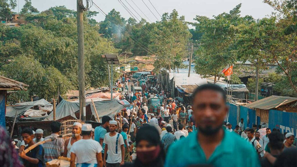Un nercato improvvisato dentro al Cox's Bazar dove ognuno vende quello che ha a disposizione. Si vede molta gente camminare in strada.