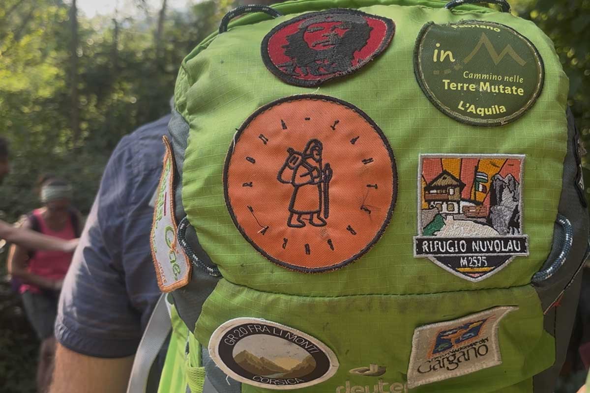 Primo piano di uno zaino con patch di ogni viaggio che ha fatto il proprietario, tra i quali c'è Terre Mutate