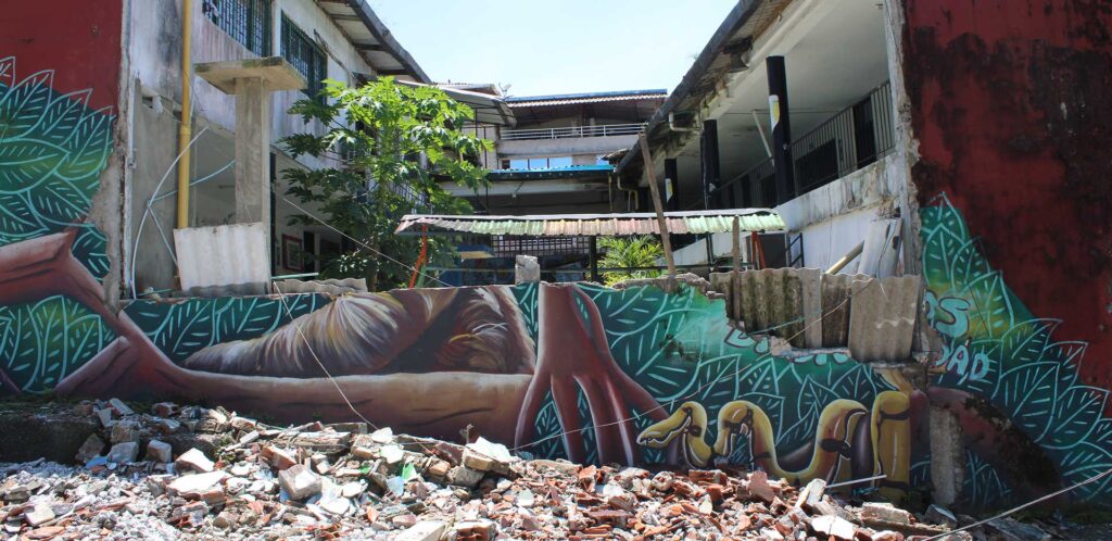 Un'abitazione crollata. Si intravede sui resti del muro un murales colorato.