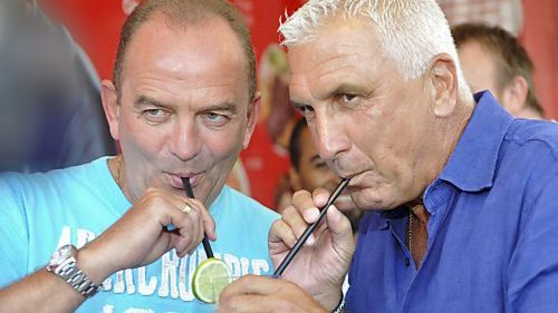 Herbert Prohaska und Hans Krankl trinken mit Strohhalmen aus einem gemeinsamen Glas