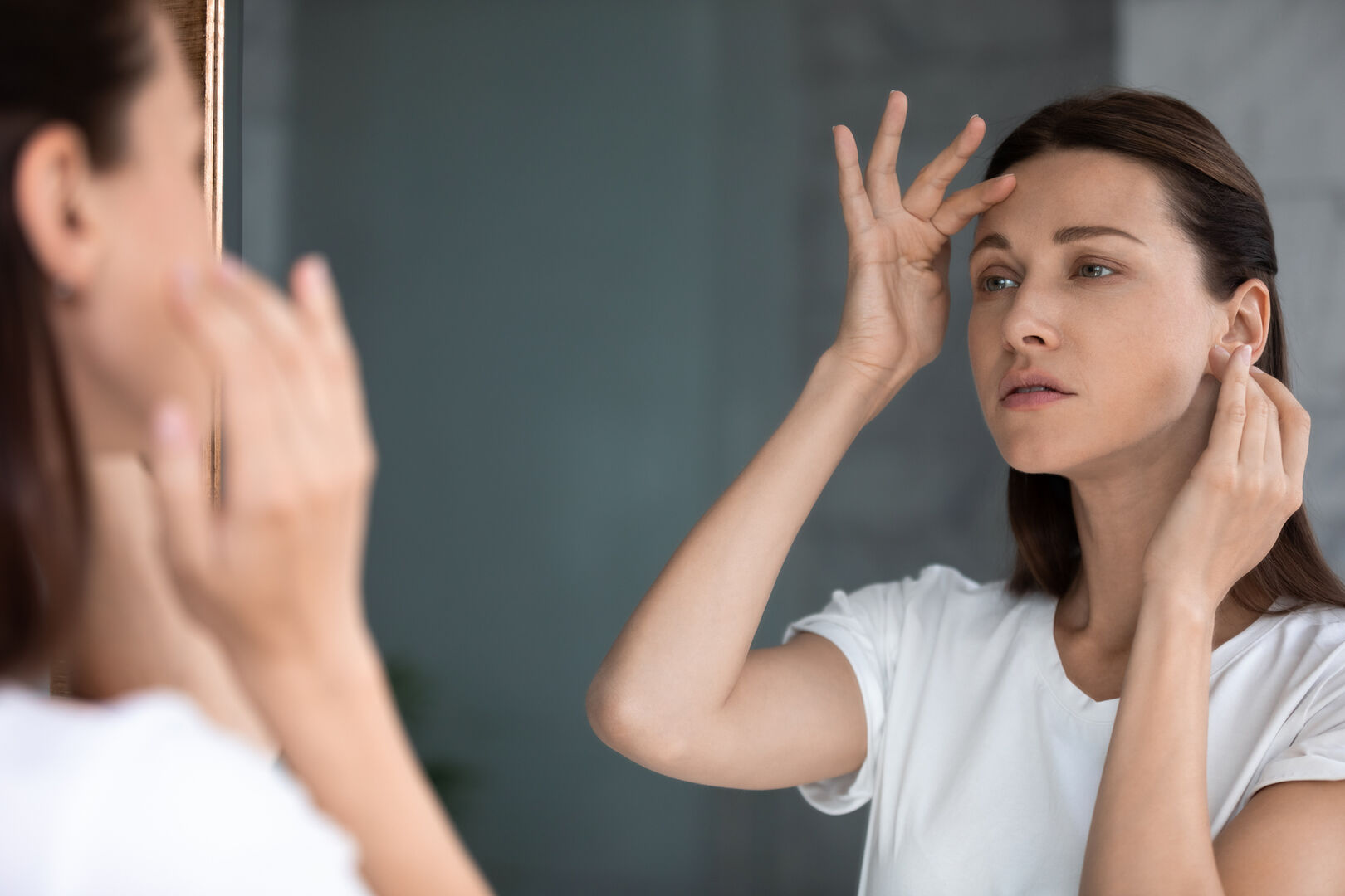 Frau sucht ihr Spiegelbild nach Falten ab