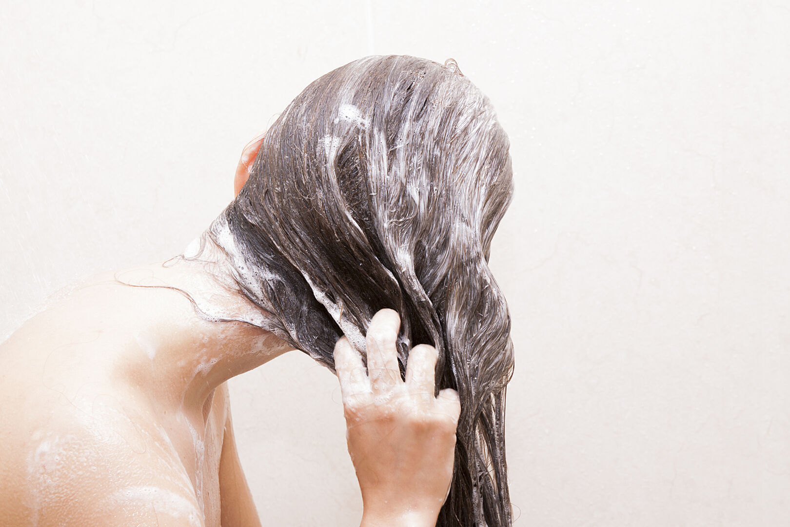 Frau schäumt sich die Haare ein