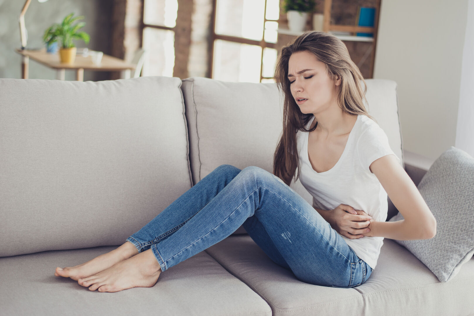 Frau mit Bauchschmerzen auf Sofa