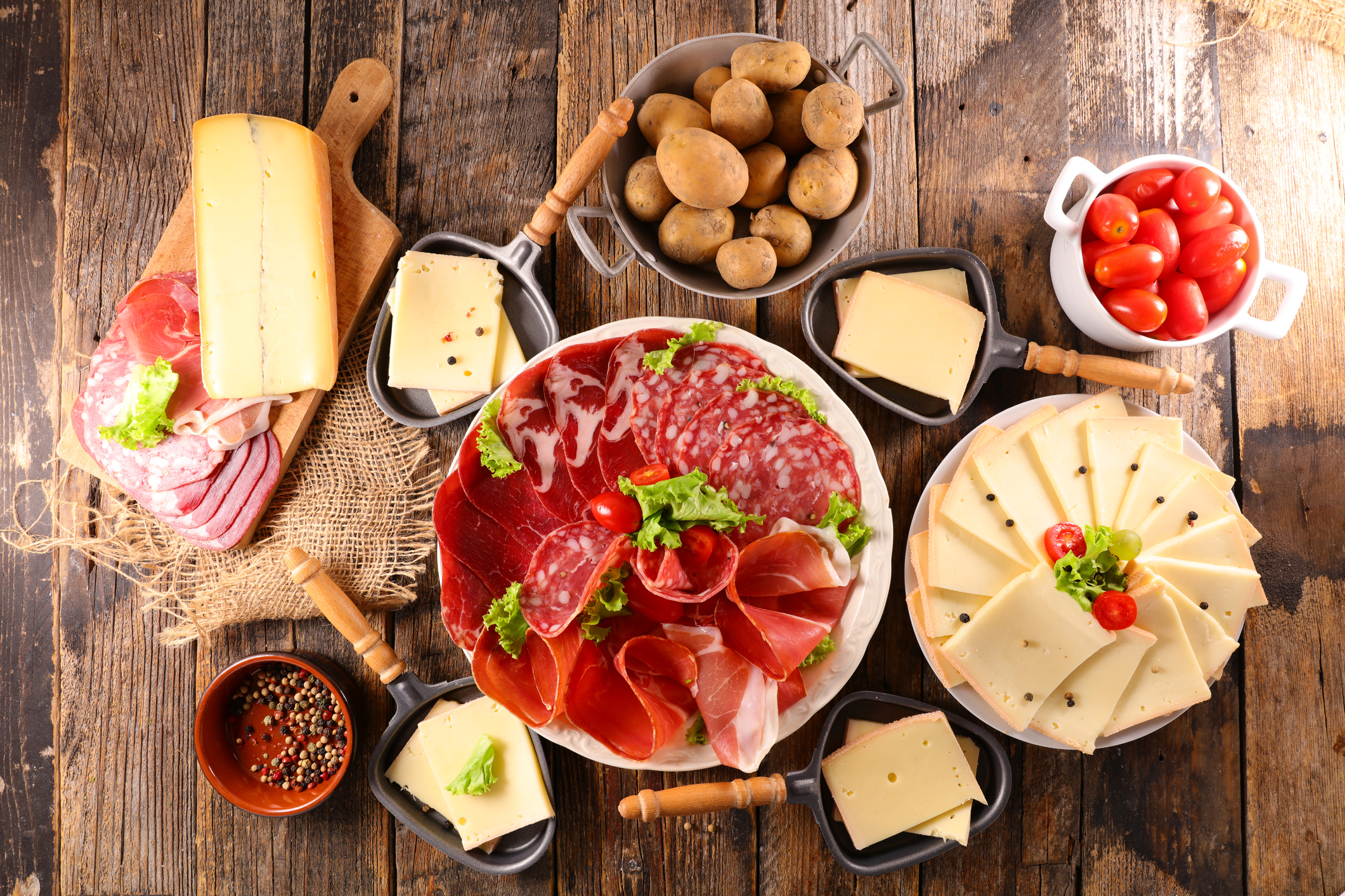 Unterschiedliche Käse- und Fleischsorten sowie Kartoffeln für ein Raclette