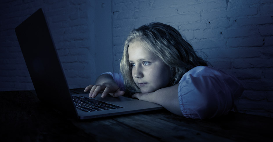 Kind starrt gebannt auf den Bildschirm eines Laptops