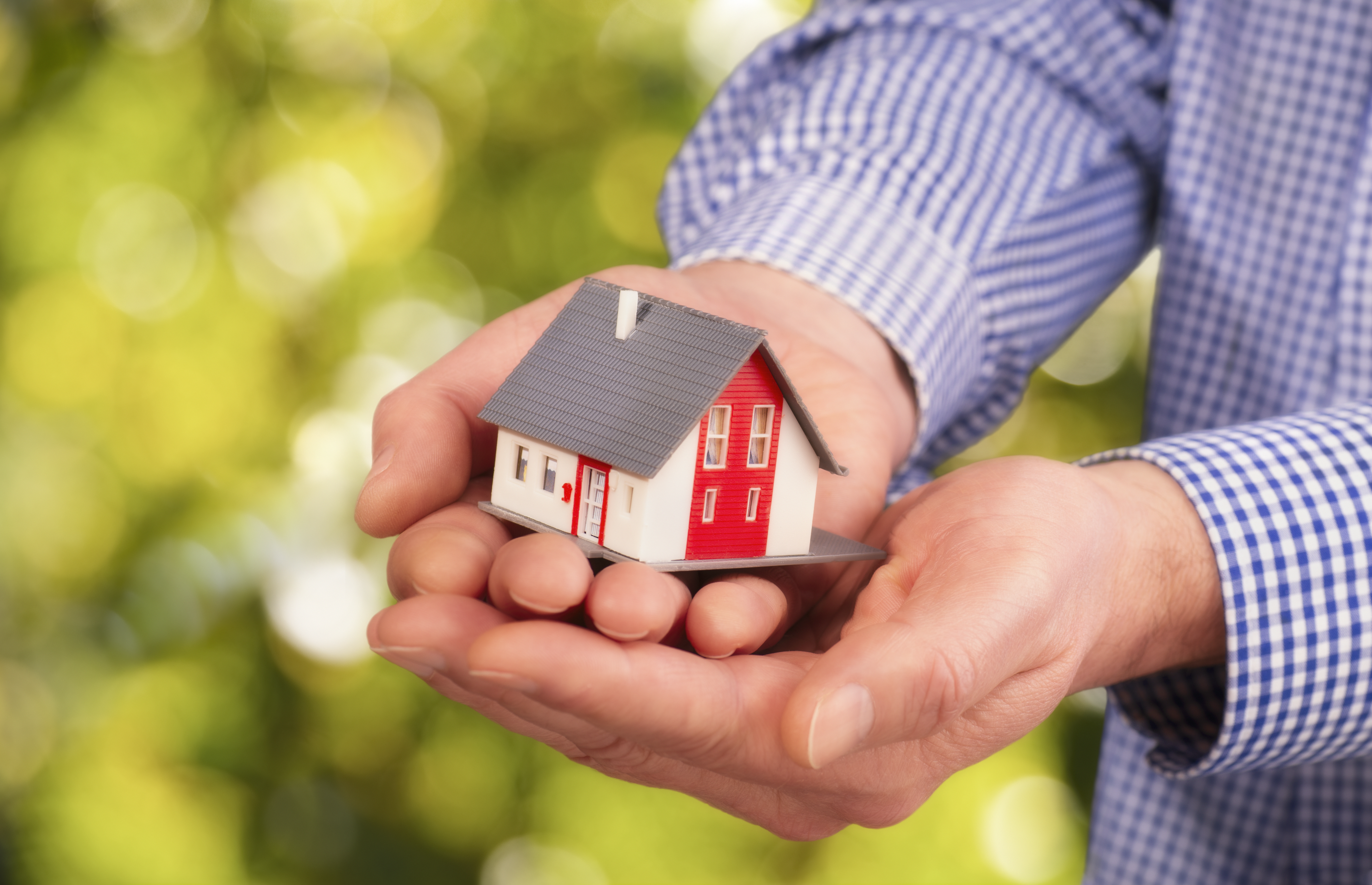 Mann hält ein Hausmodell