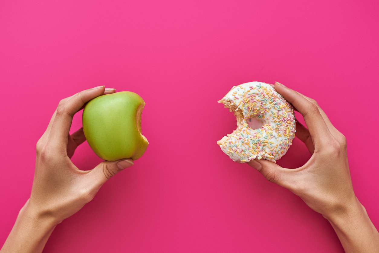 Links ein angebissener Apfel, rechts ein angebissener Donout.