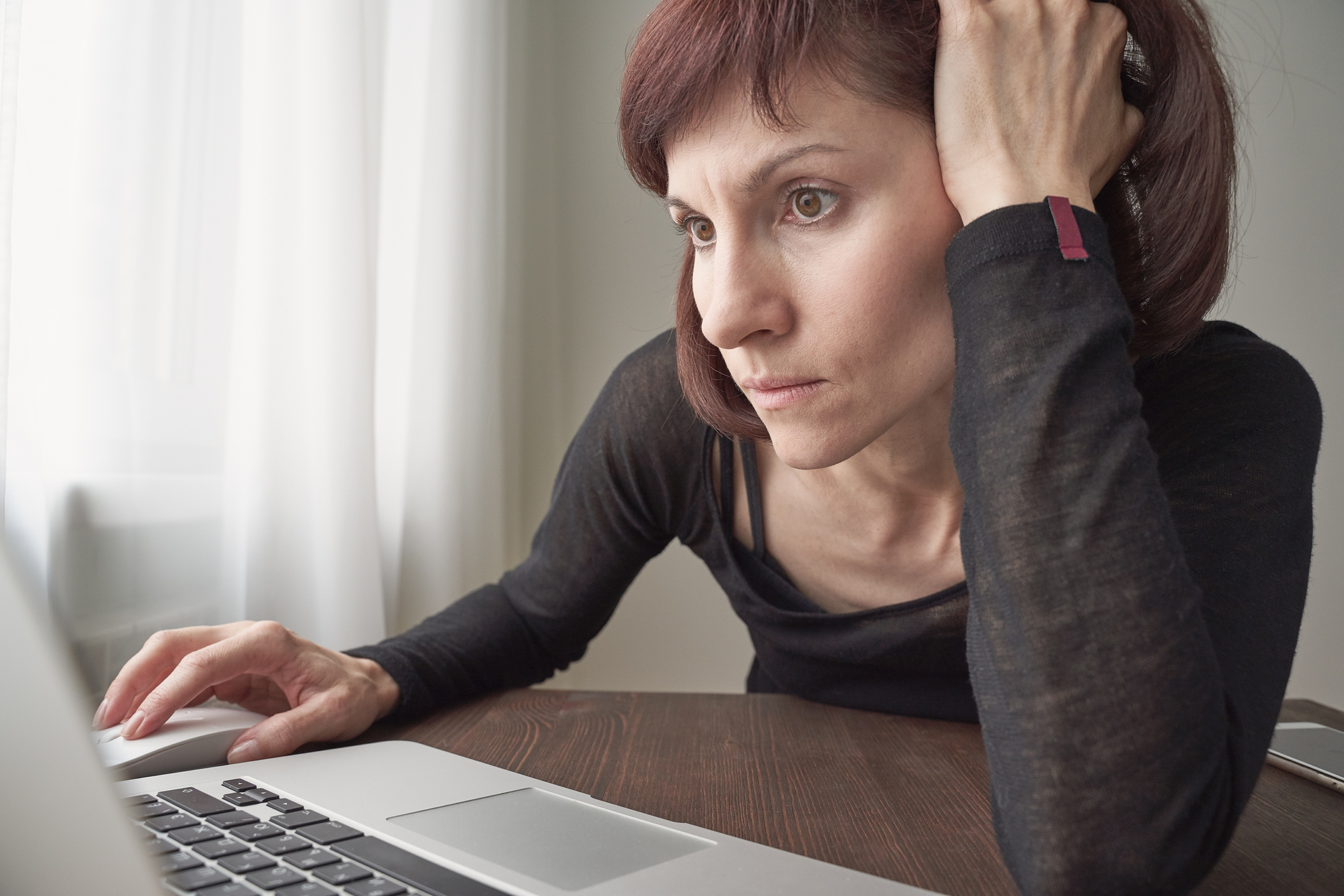 Frau am Schreibtisch starrt in den Laptop
