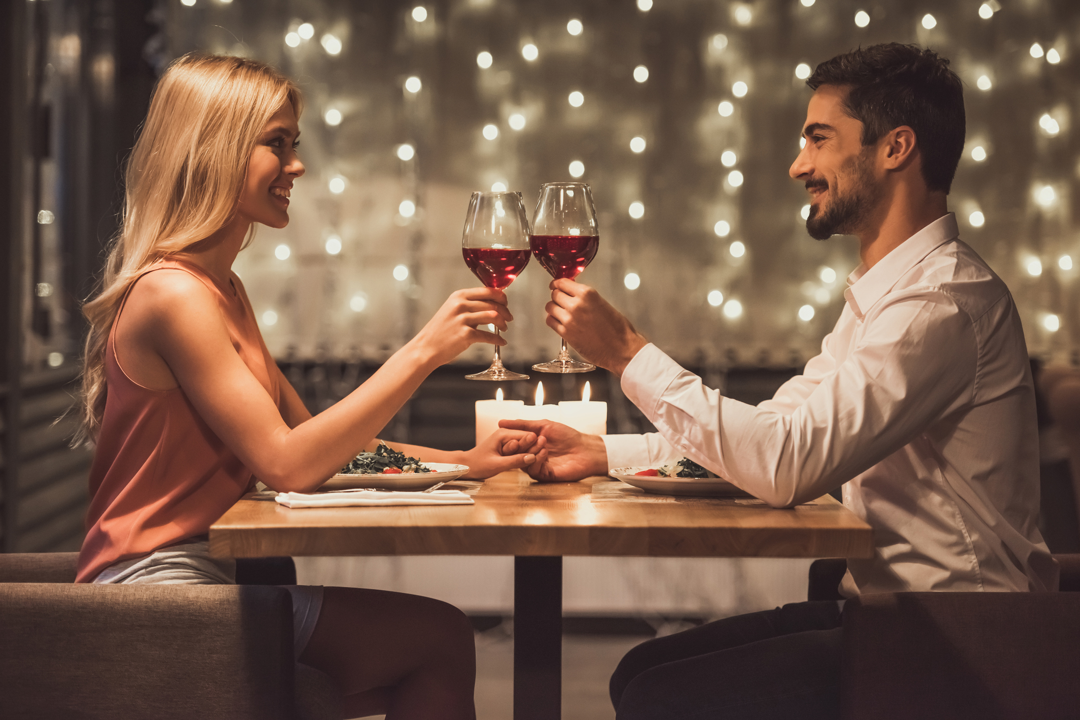 Ein Pärchen stößt mit Rotwein auf ein feierliches Abendessen an.