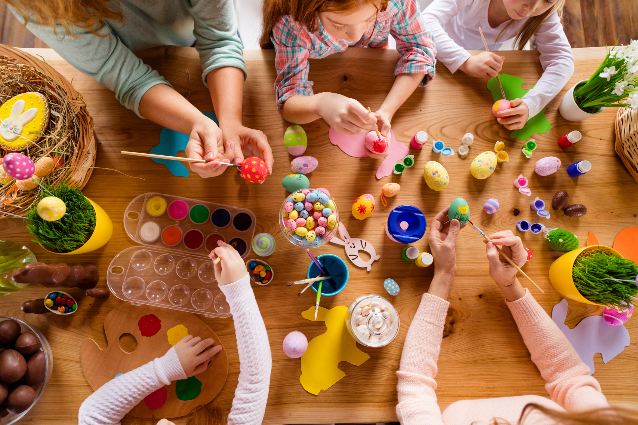 Eine Vogelperspektive auf einen Tisch, an dem Kinder mit österlichem Bastelmaterial spielen