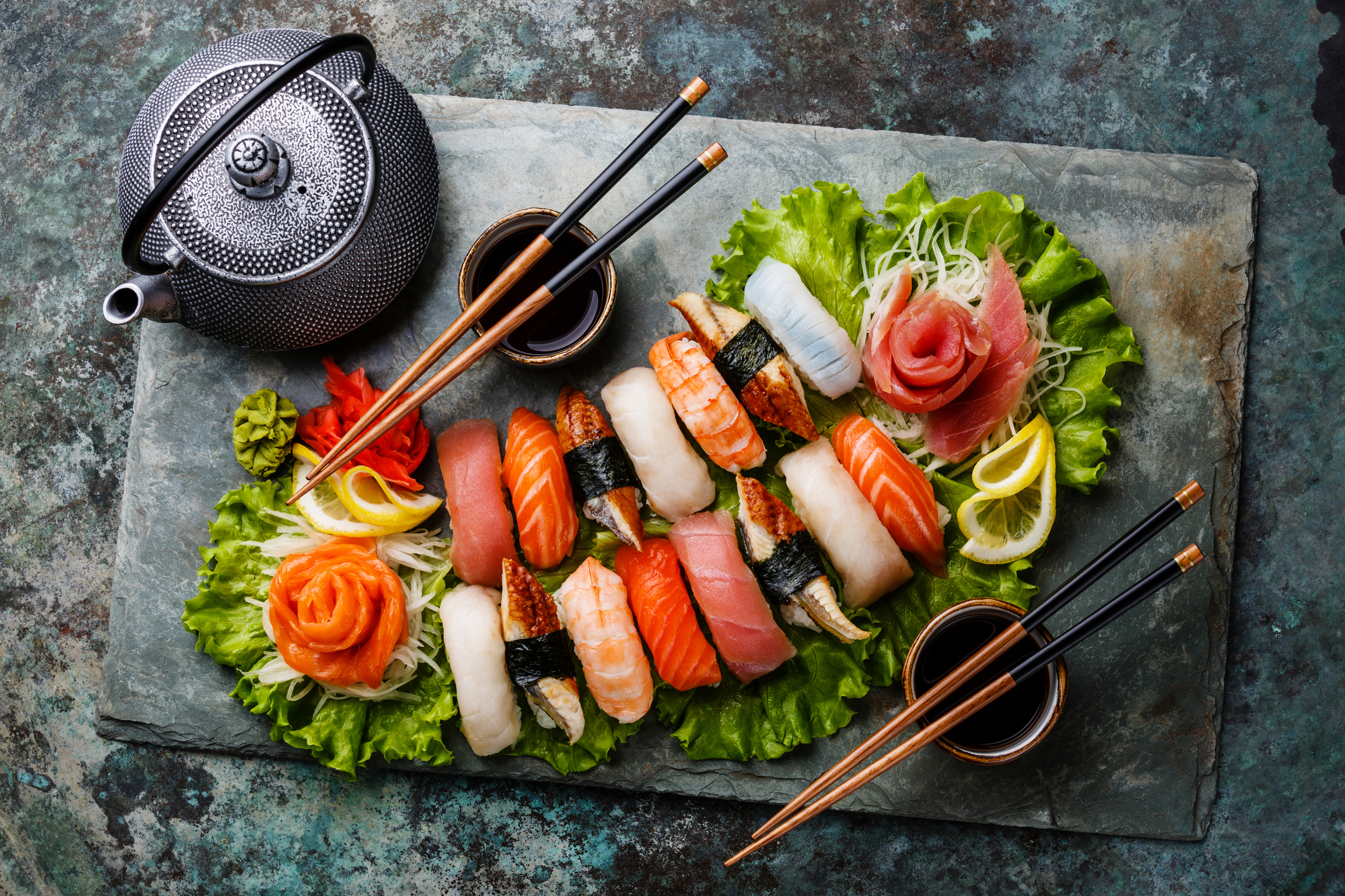 Eine Sushiplatte mit Essstäbchen, Schalen für die Sojasauce und einem Teekessel