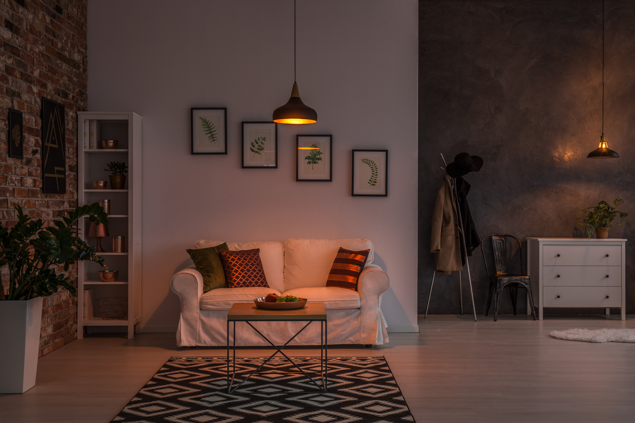 Ein modern gestaltetes Wohnzimmer, das von nur einer schwachen Deckenlampe bescheiden ausgeleuchtet wird