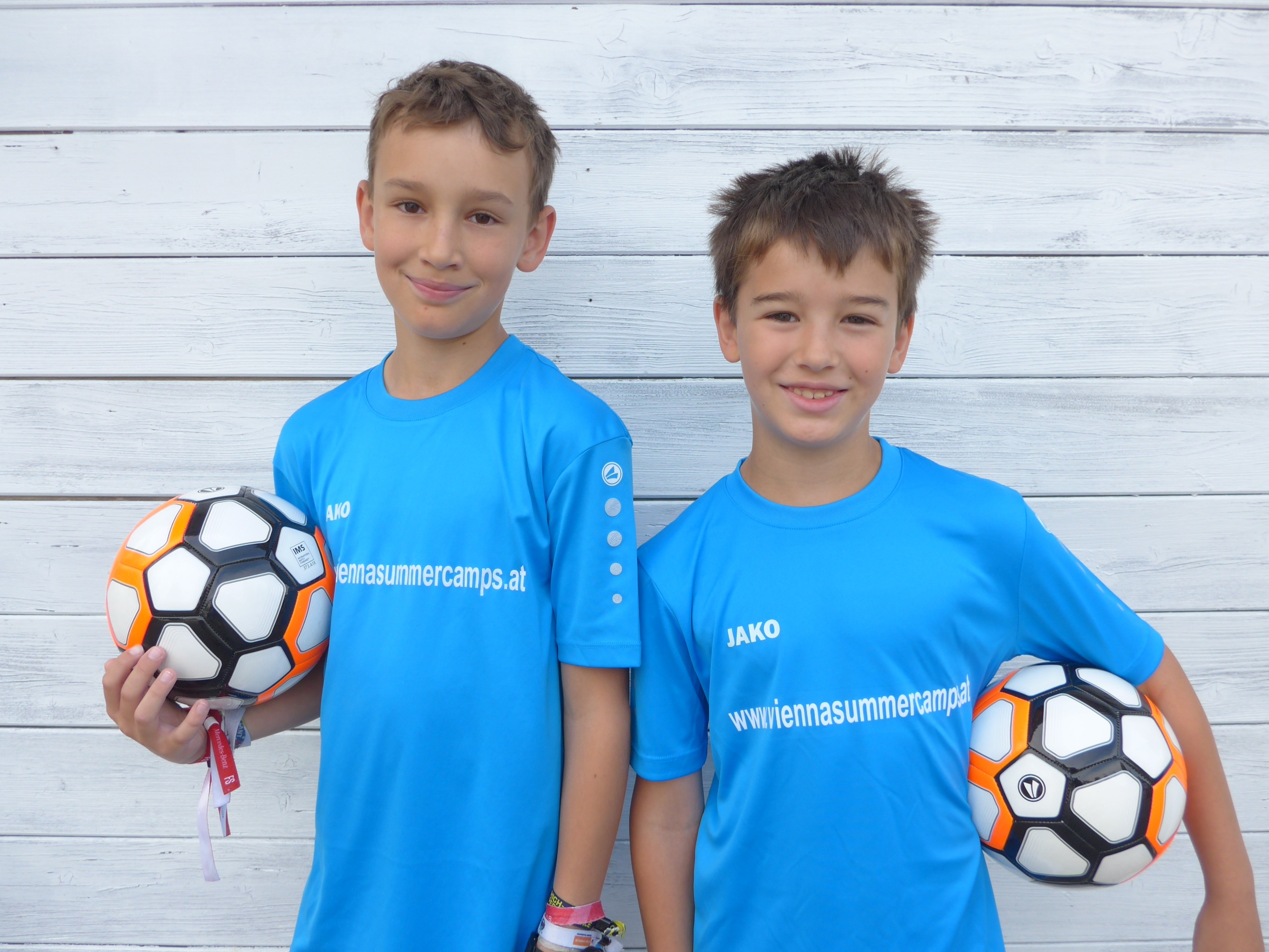Zwei Buben mit blauem Shirt mit einem Fußball