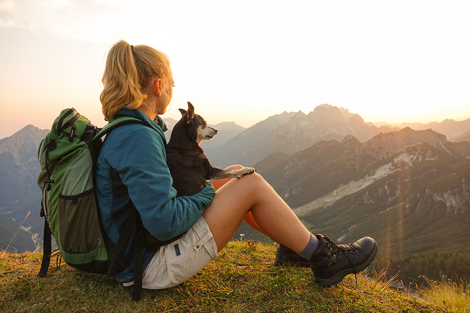 Frau und Hund machen Pause beim Wandern. Credit: iStock.com/helivideo
