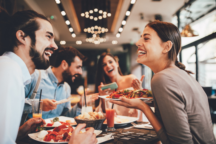 Lachende Gesicheter rund um den Restaurant-Tisch