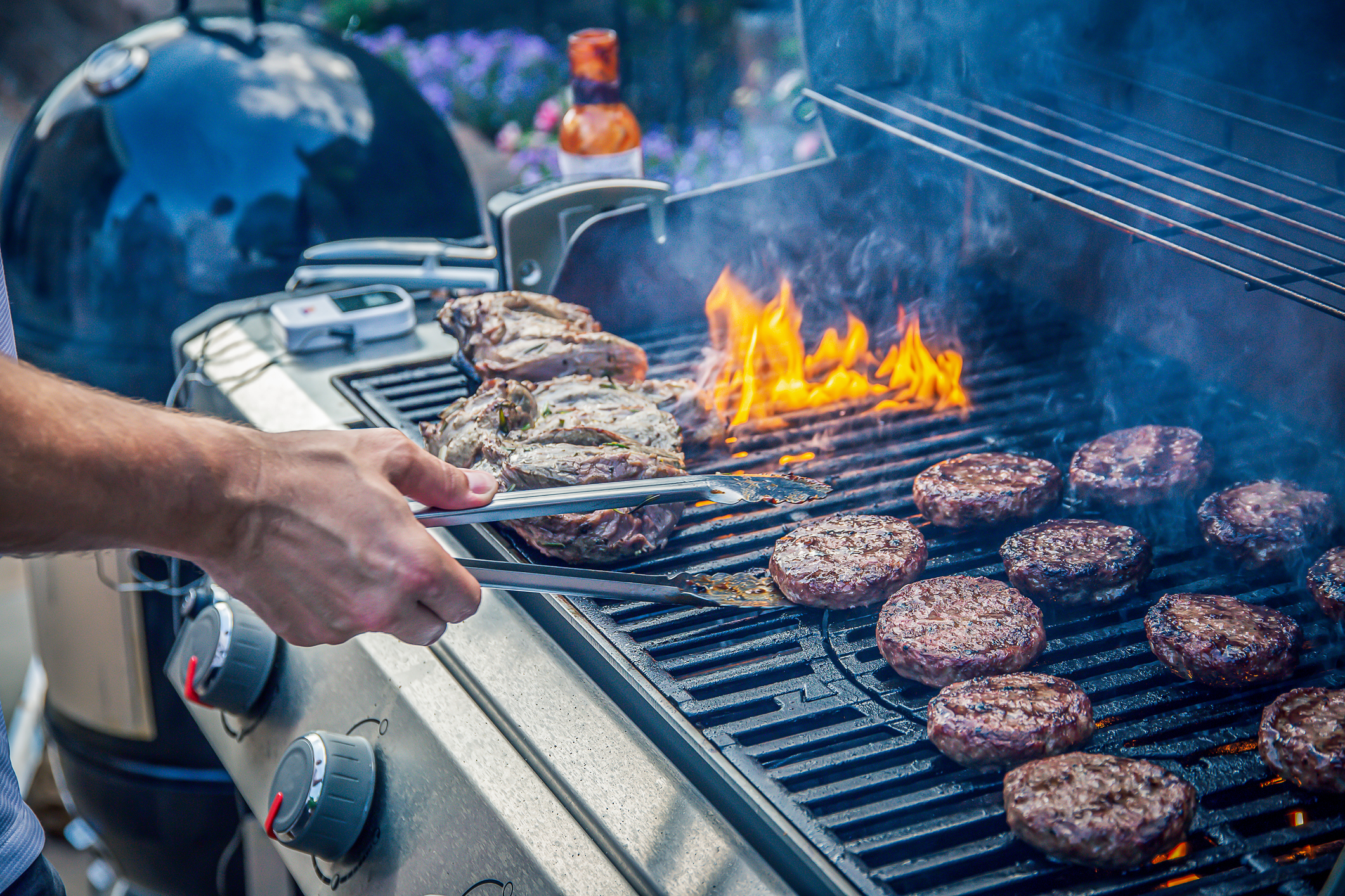 Nahaufnahme eines rauchenden Grills, auf den unterschiedliche Fleischsorten gelegt wurden
