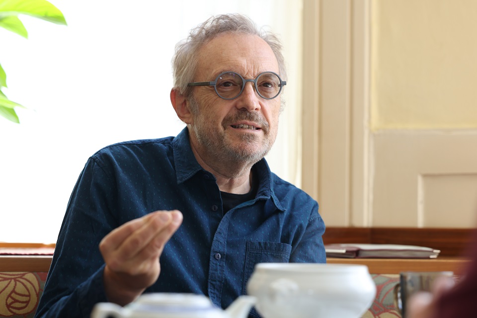 Josef Hader gestikuliert im Gespräch. Vor ihm stehen eine Suppenterrine und eine Kanne Tee.