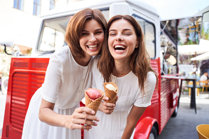 Zwei Freundinnen lachen mit einer Eistüte