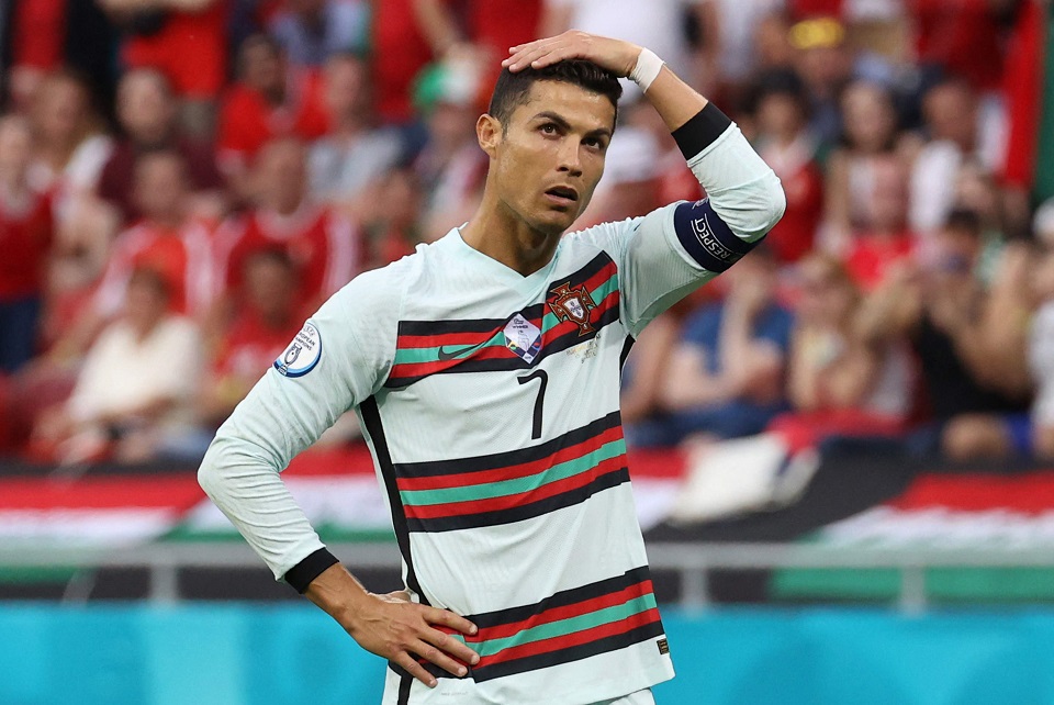 Cristiano Ronaldo im Dress der portugiesischen Nationalmannschaft hat eine Hand in die Hüfte gestemmt und greift sich mit der anderen fragend auf den Kopf.