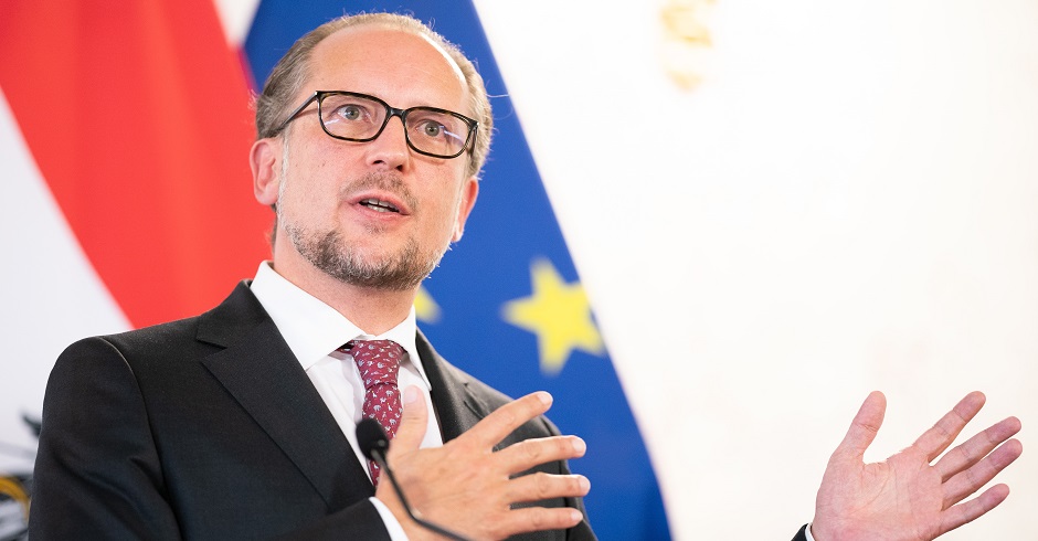 Außenminister Aleander Schallenberg spricht vor einer Österreich- und einer EU-Flagge.