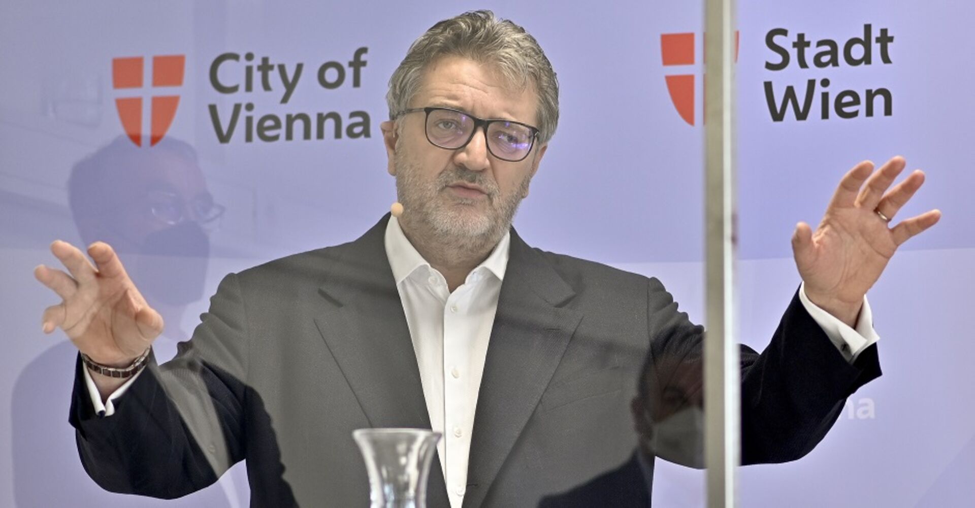 Gesundheitsrat Peter Hacker bei einer Pressekoferenz. Er spricht und hat die Arme in der Luft.