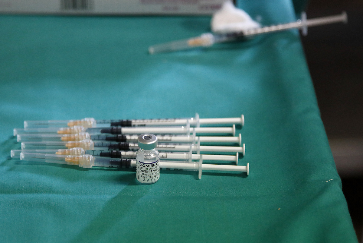 Spritzen und ein Fläschchen mit Impfstoff auf sterilem grünen Tuch