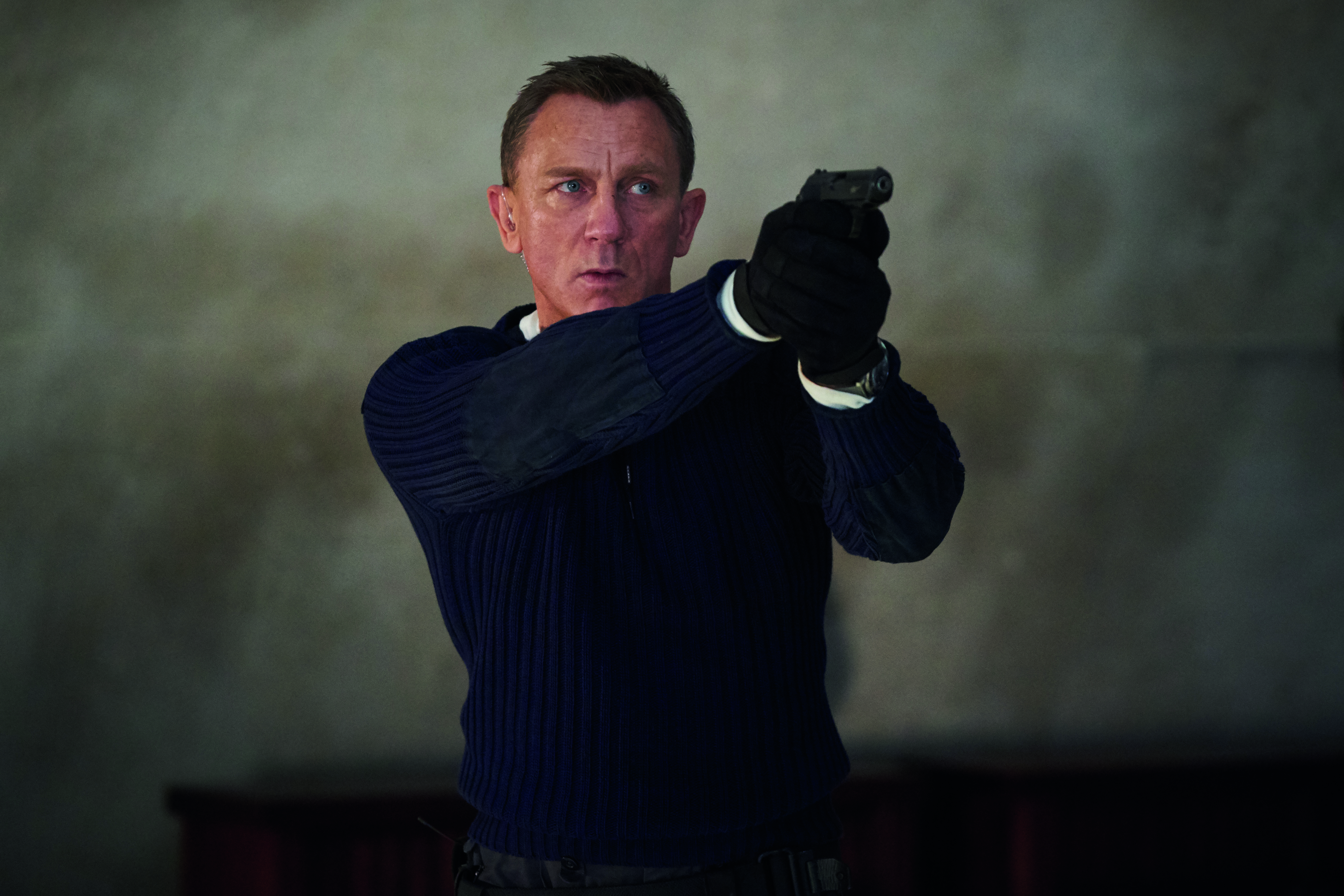 Daniel Craig legt als James Bond mit einer Pistole auf einen sich nicht im Bild befindenden Gegner an