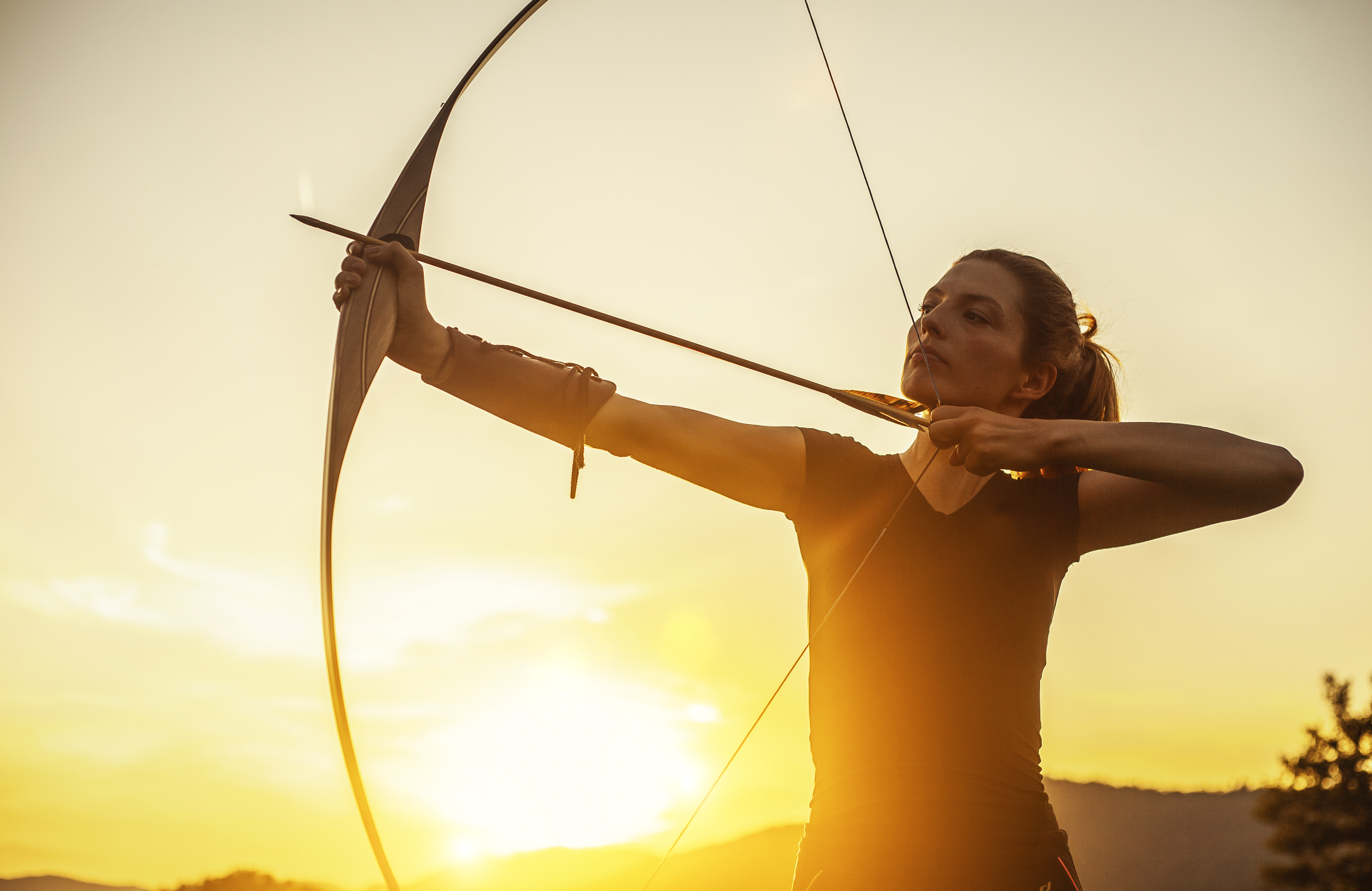 Frau mit Bogen im Sonnenuntergang