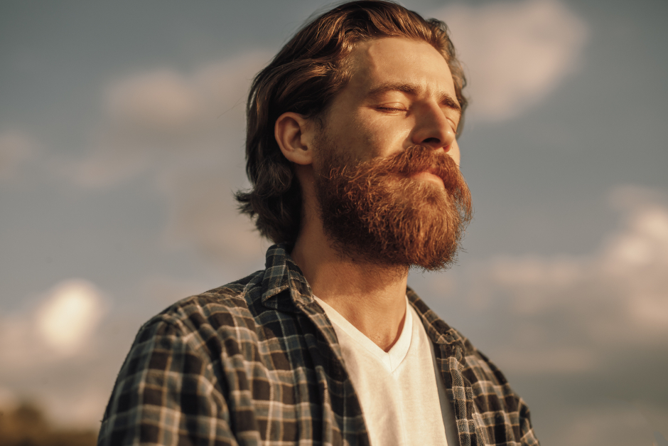Vollbärtiger Mann mit geschlossenen Augen genießt die Sonne | Credit: iStock.com/max-kegfire
