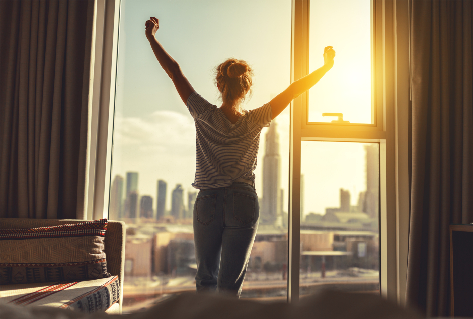 Nach dem Aufstehen macht eine Frau bei offenem Fenster Streckübungen | Credit: iStock.com/evgenyatamanenko