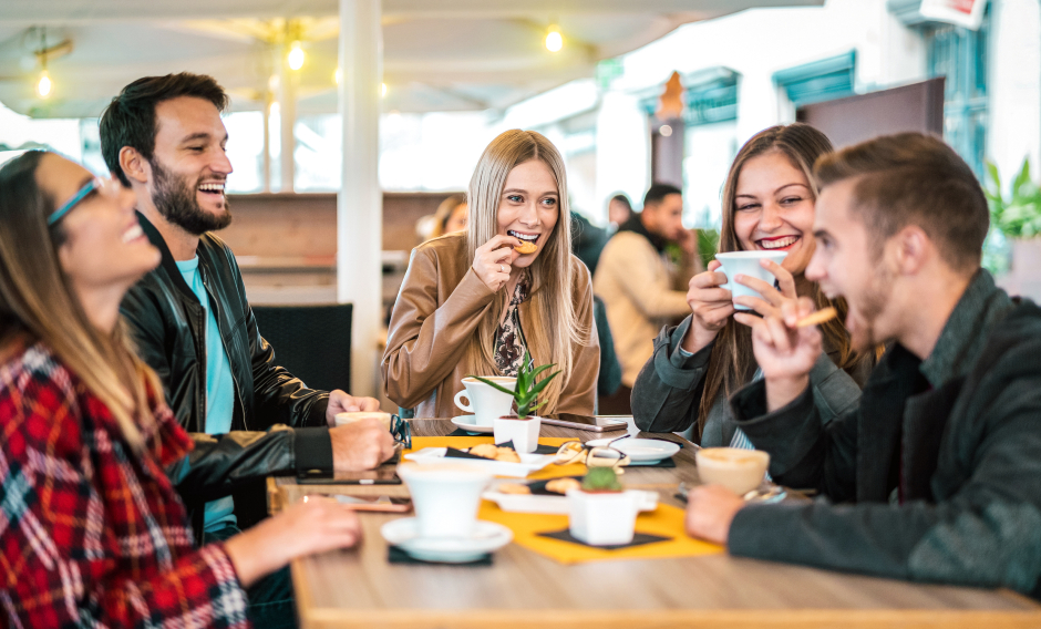 Eine Gruppe junger Mädchen und Burschen beim gemeinsamen Essen im Fastfood-Lokal | Credit: iStock.com/ViewApart
