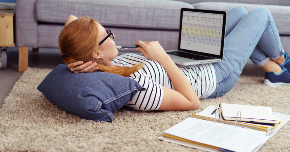 Junge Frau mit Notebook auf dem Schoß lernt im Liegen | Credit: iStock.com/stockfour