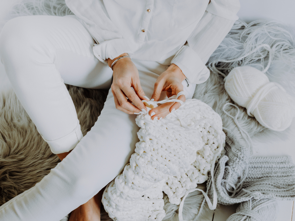 Frau häkelt eine weiße Decke | Credit: iStock.com/HannesEichinger