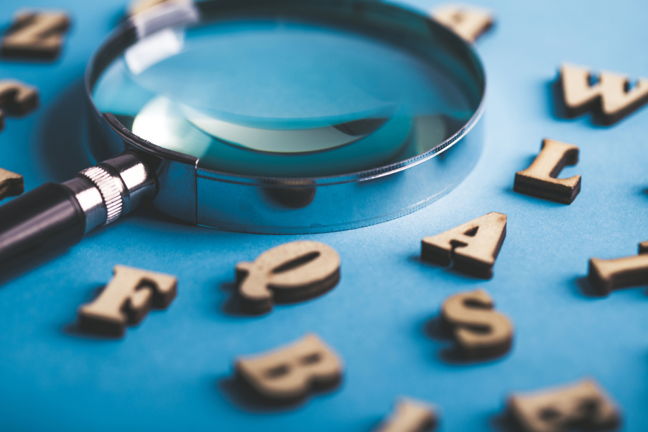 Buchstabensalat mit Lupe auf blauem Untergrund | Credit: iStock.com/ChristianChan