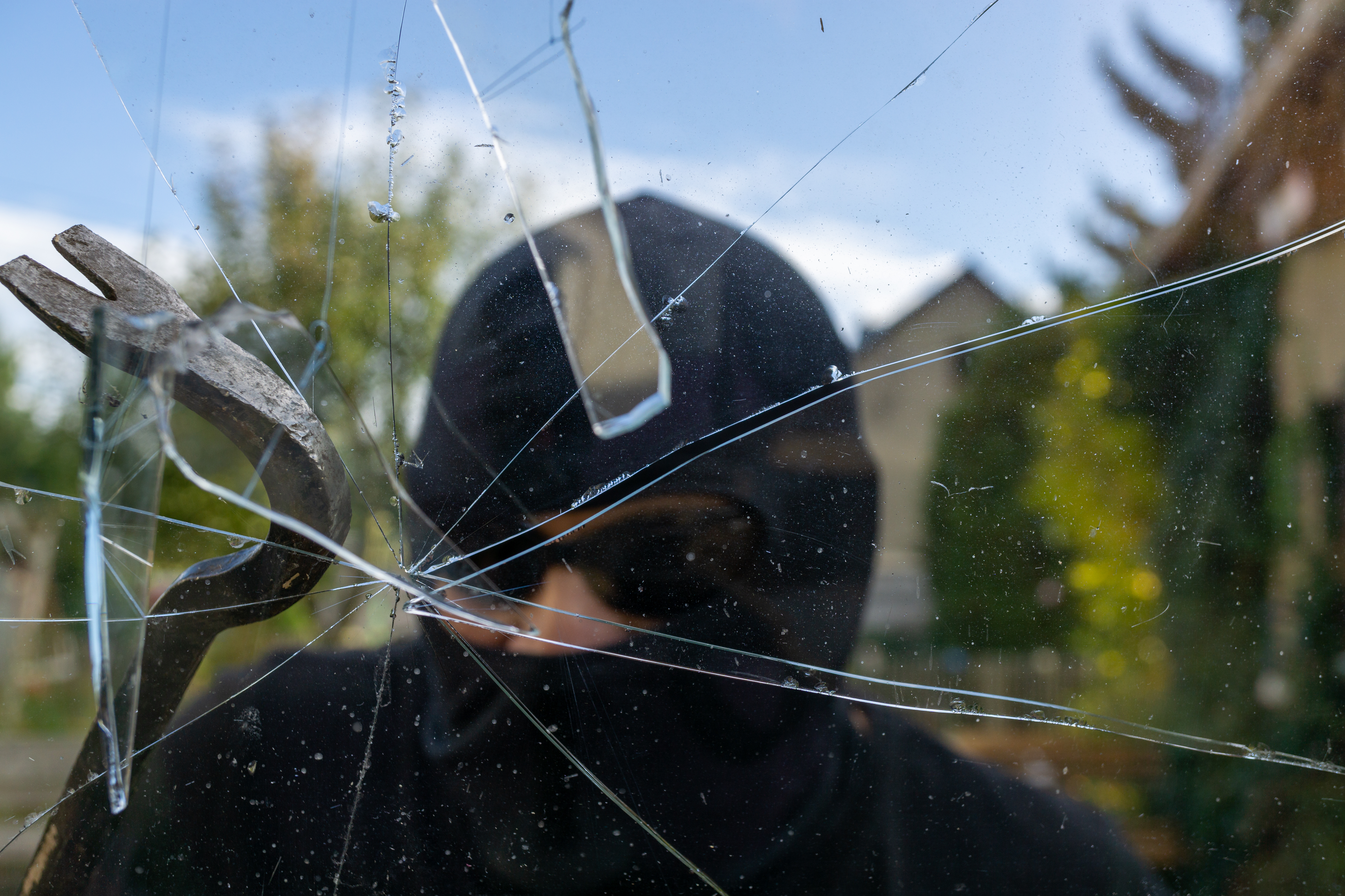 Einbrecher schlägt ein Fenster ein