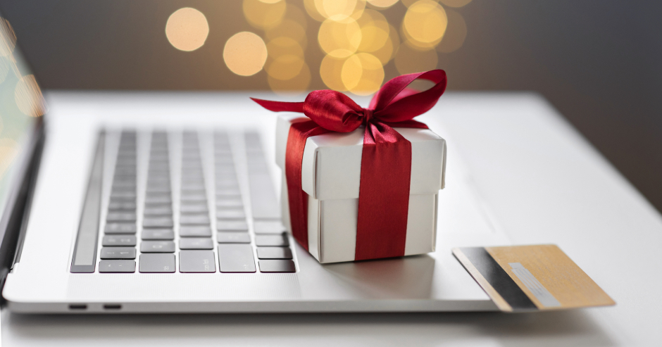 Weihnachtspäckchen und Kreditkarte liegen auf einer Notebook-Tastatur | Credit: iStock.com/Poike