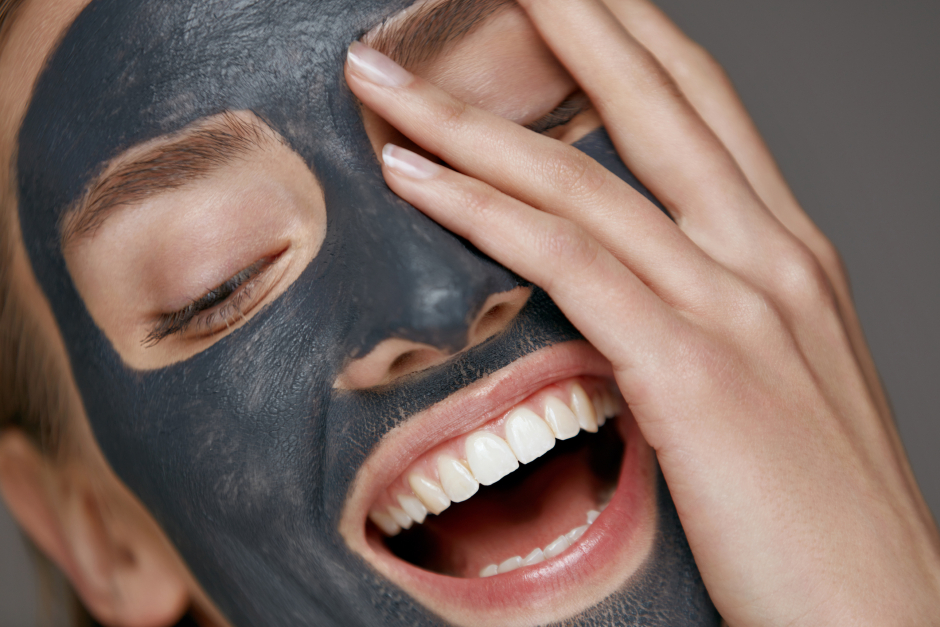 Fröhliche junge Frau macht sich eine Gesichtsmaske | Credit: iStock.com/puhhha