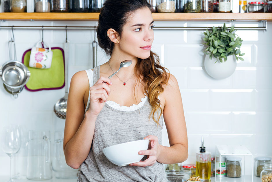 Junge Frau genießt ein gesundes Frühstück in ihrer Küche | Credit: iStock.com/nensuria