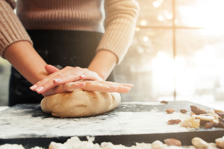 Eine Frau knetet einen Lebkuchenteig durch | Credit: iStock.com/golubovy
