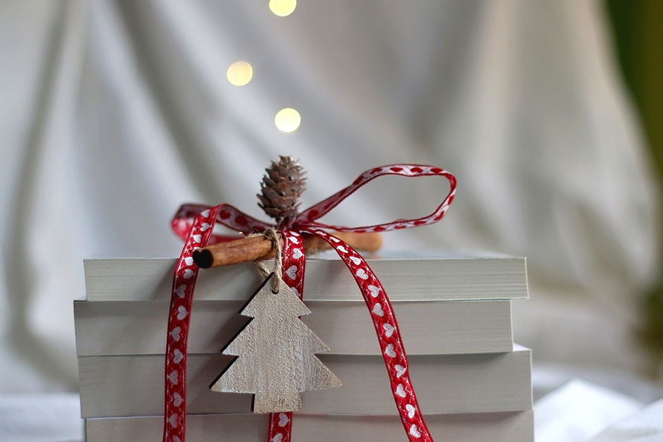 Buchstapel, zusammengehalten mit einem weihnachtlich dekorierten Geschenkband | Credit: iStock.com/Jelena990