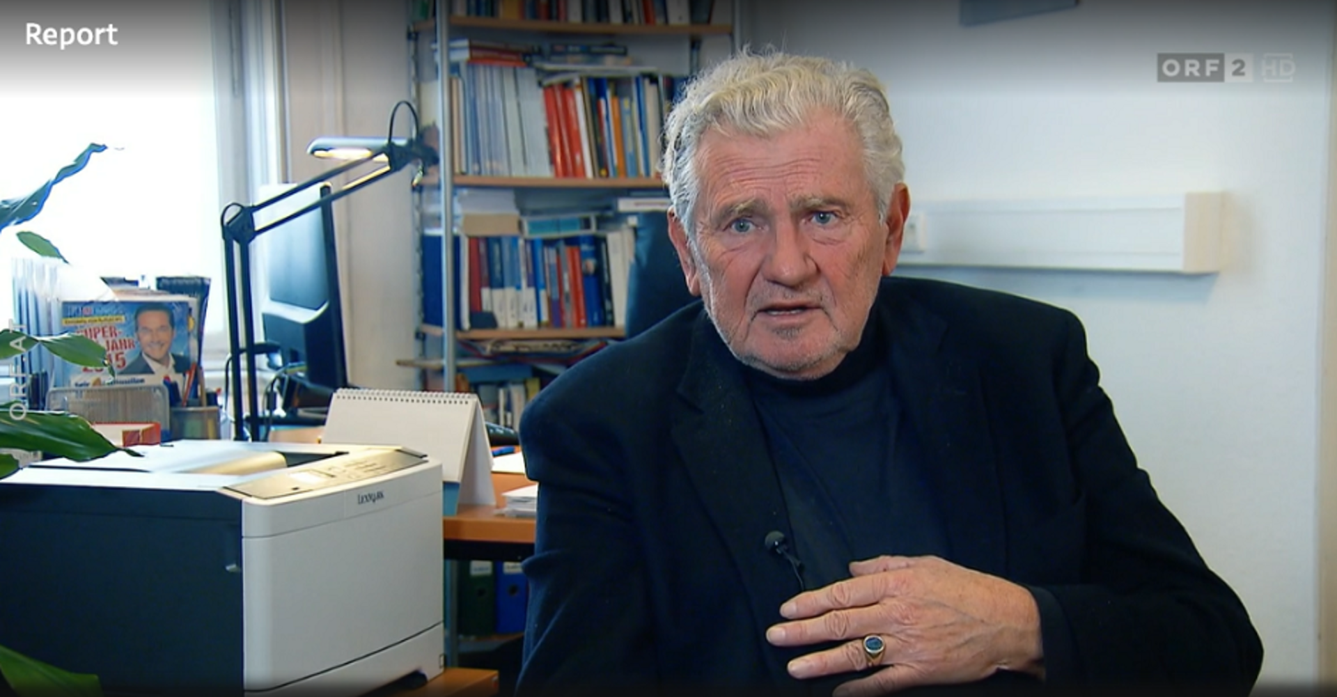 Ein Screenshot aus der Sendung Report. Andreas Mölzer an seinem Schreibtisch im Interview mit dem ORF.