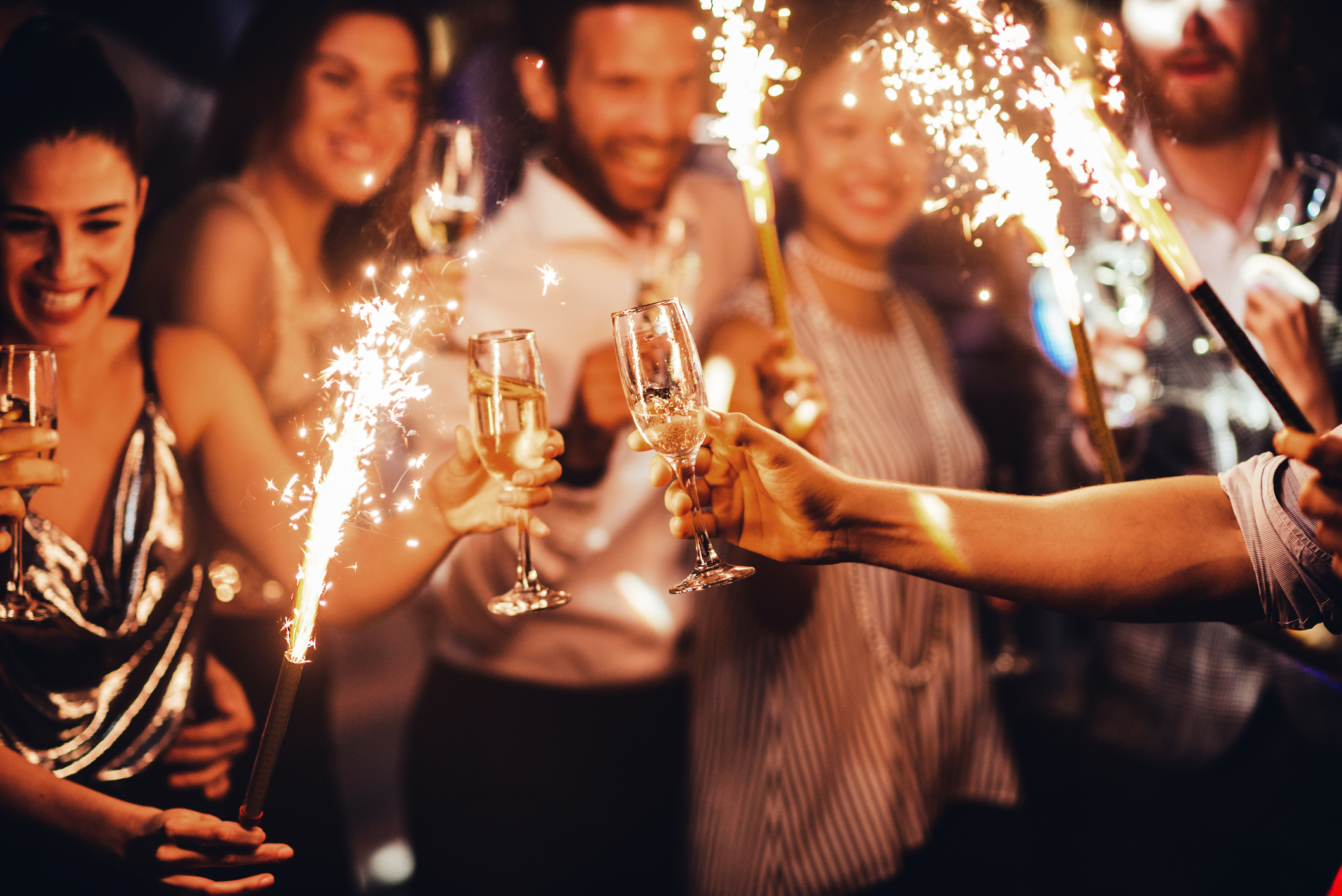 Menschen stoßen mit Champagner an und halten Wunderkerzen in Händen